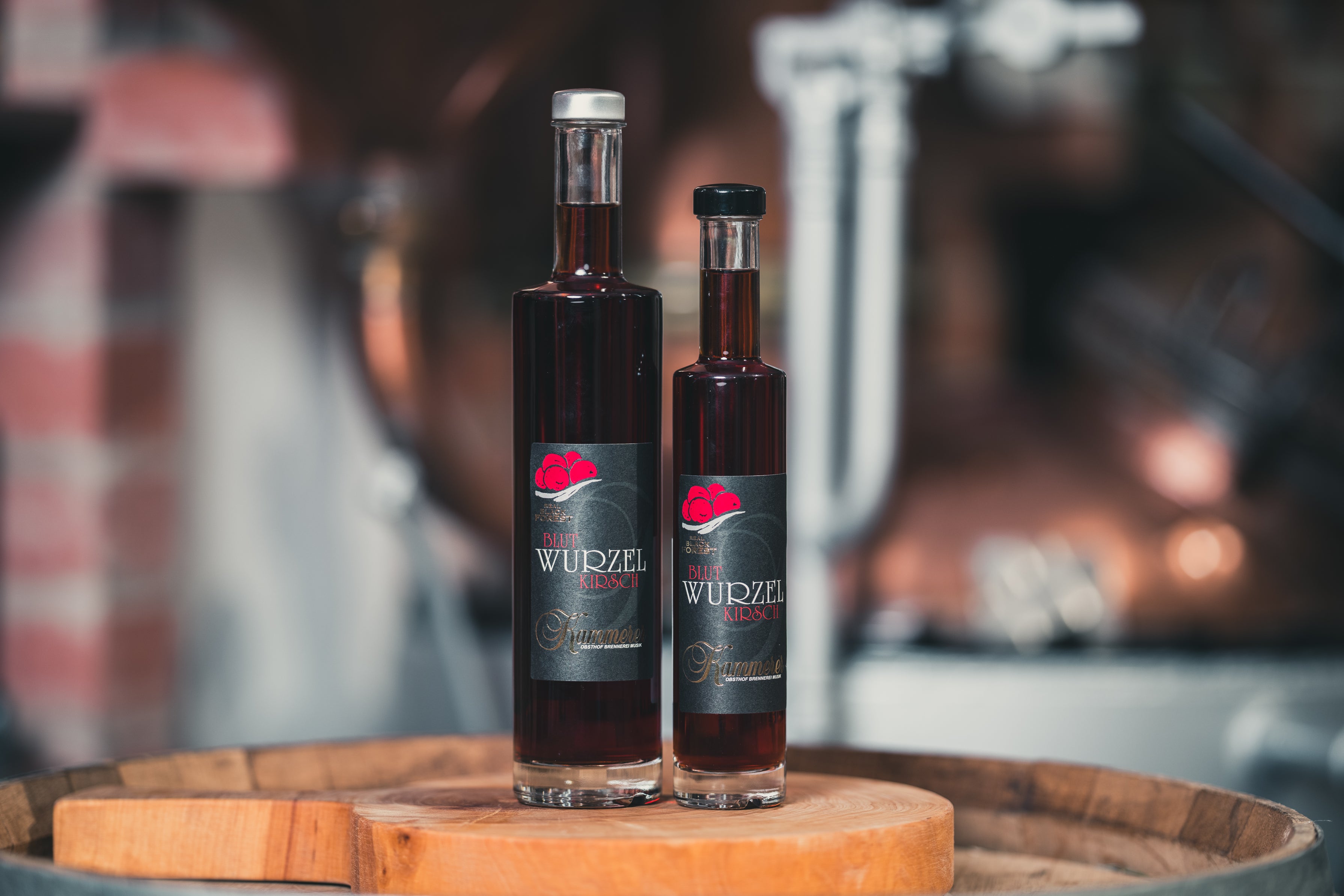 Zwei Blut Wurzel Kirsch Schnäpse auf einem Holzfass von RealBlackForest, perfekt für den Schwarzwald Genuss