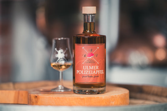 Ulmer Polizeiapfel auf einem Holzfass von RealBlackForest mit Schnapsglas, Ulmer Brand mit traditionellem Polizeiapfel